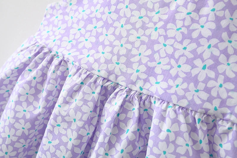 A purple baby girl summer dress featuring a white floral pattern and ruffled details.