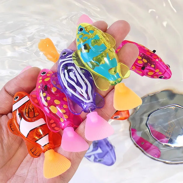 A hand holds several colorful light-up bath toys shaped like tropical fish.