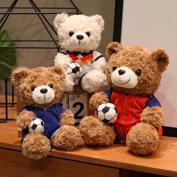 A collection of three cute football bear plush toys, including a large white bear, a brown bear, and a reddish-orange bear.