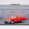 A red 1967 Chevrolet Impala diecast model car in pull-back action on a gray surface.