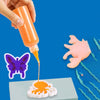 A hand is squeezing orange liquid from a bottle onto a white silicone mold, creating a butterfly shape.