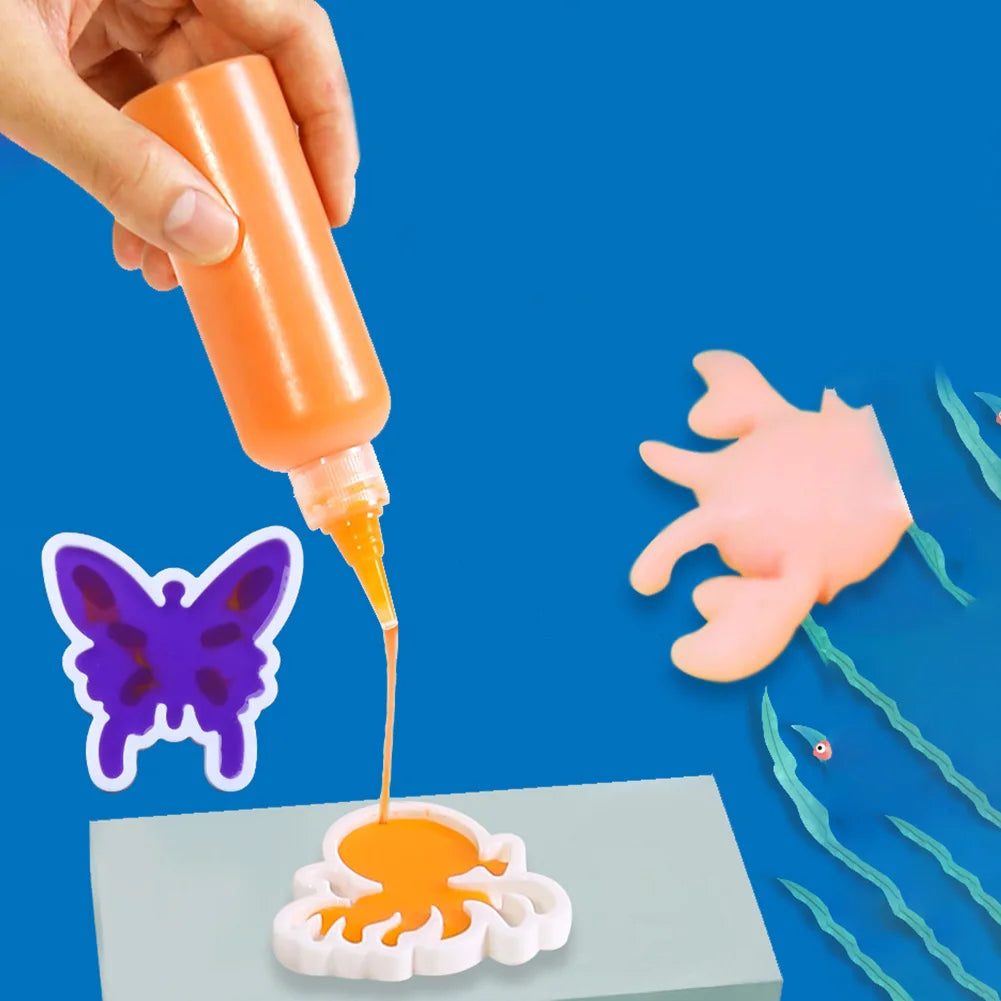 A hand is squeezing orange liquid from a bottle onto a white silicone mold, creating a butterfly shape.