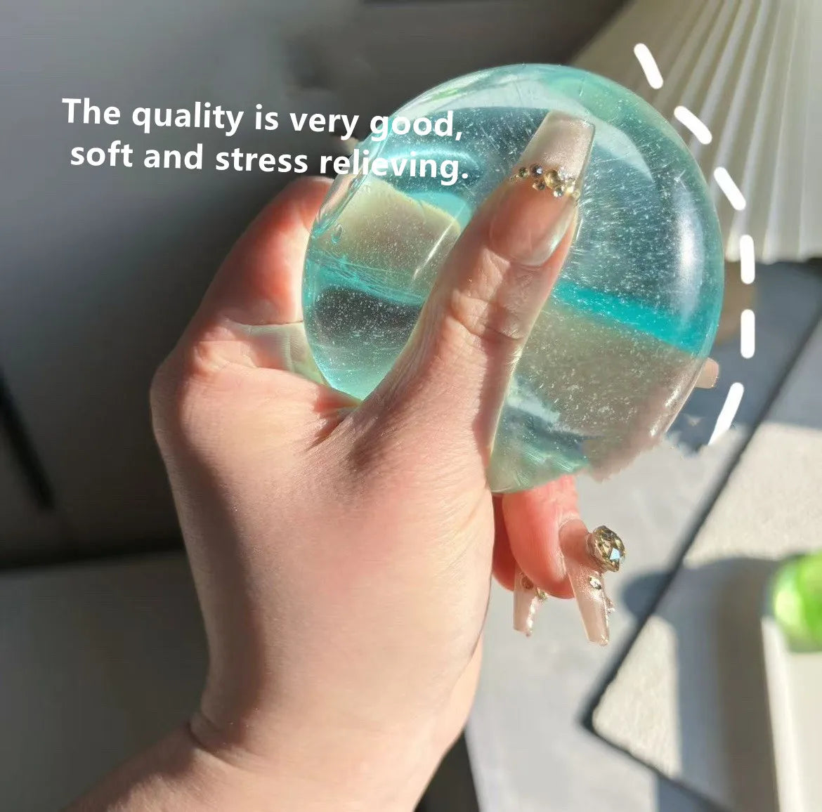 A hand holds a translucent blue and green squishy stress cube, demonstrating its smooth texture.