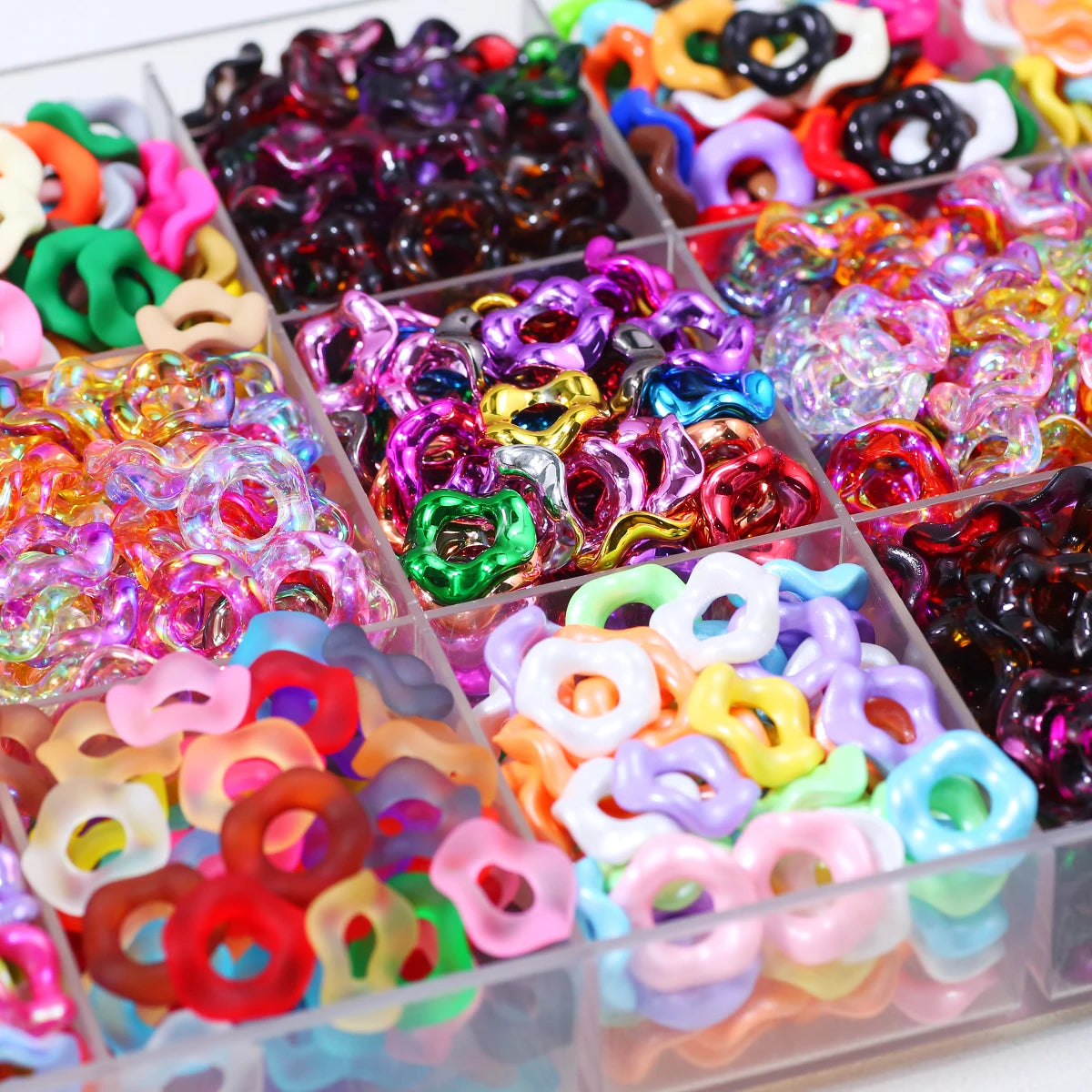 A collection of colorful wave-patterned acrylic beads in various shades and shapes arranged in small compartments.