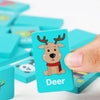 A hand holds a wooden puzzle piece featuring a deer design in blue and pink on a white background.
