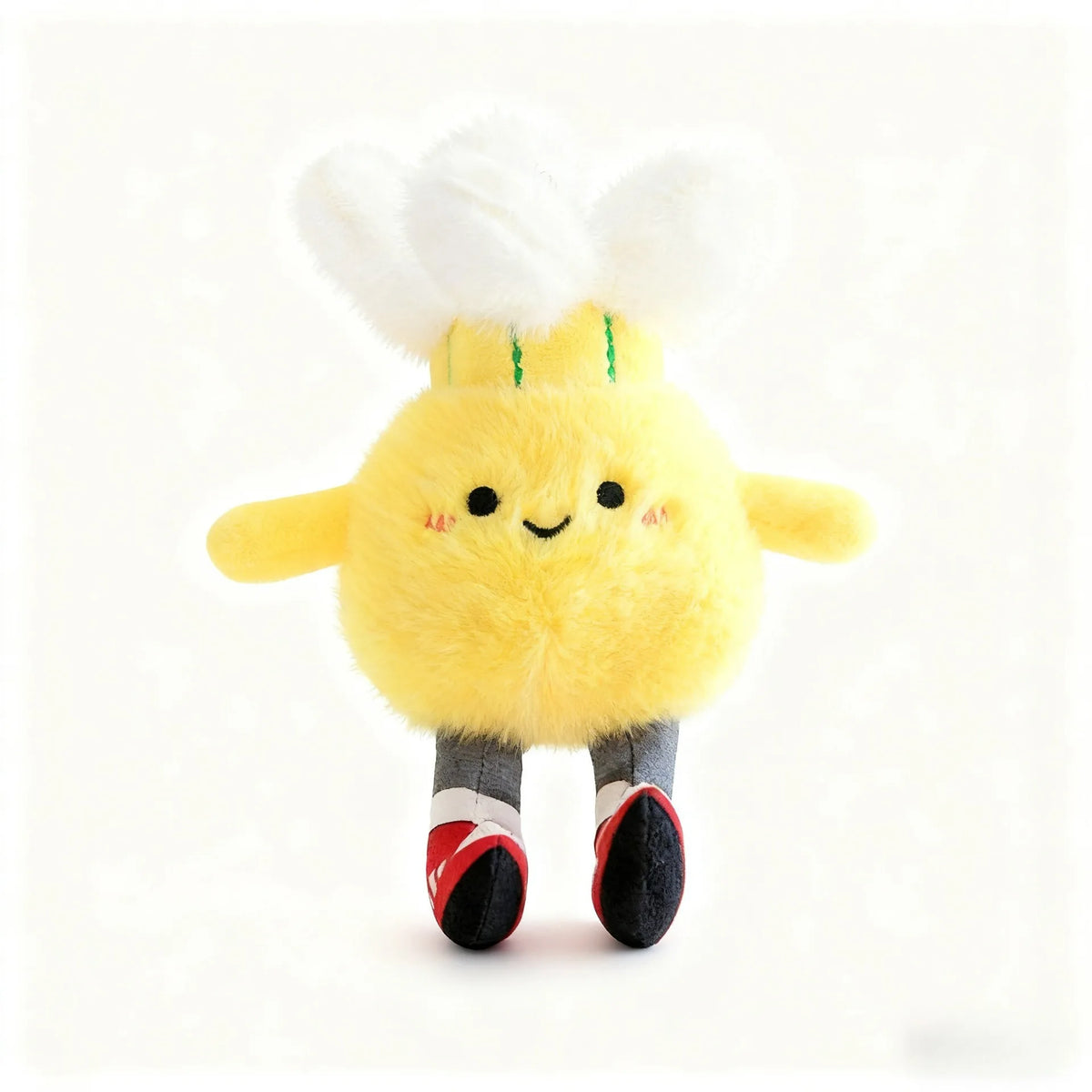A yellow plush sports ball keychain with white feathers and black feet.
