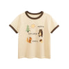 A light beige short-sleeve cotton t-shirt featuring a graphic of a pine tree, sun, and a bear figure with the text Happy Expl