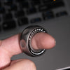 A hand holds a dark gray magnetic fidget ring, demonstrating finger gyro gameplay.