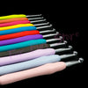 A collection of colorful crochet hooks and knitting needles arranged in a diagonal line against a black background.