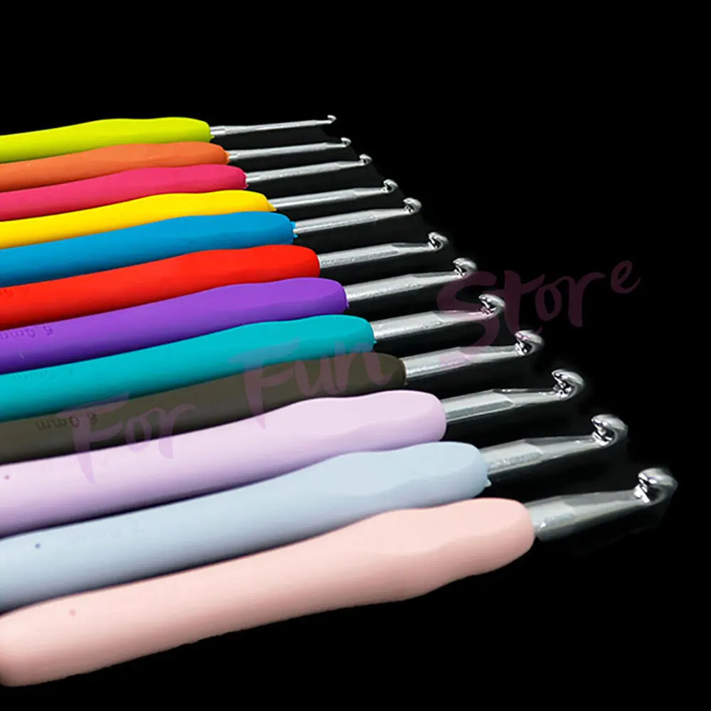 A collection of colorful crochet hooks and knitting needles arranged in a diagonal line against a black background.