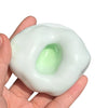 A hand holds a translucent, squishy sand stress ball with a green center.