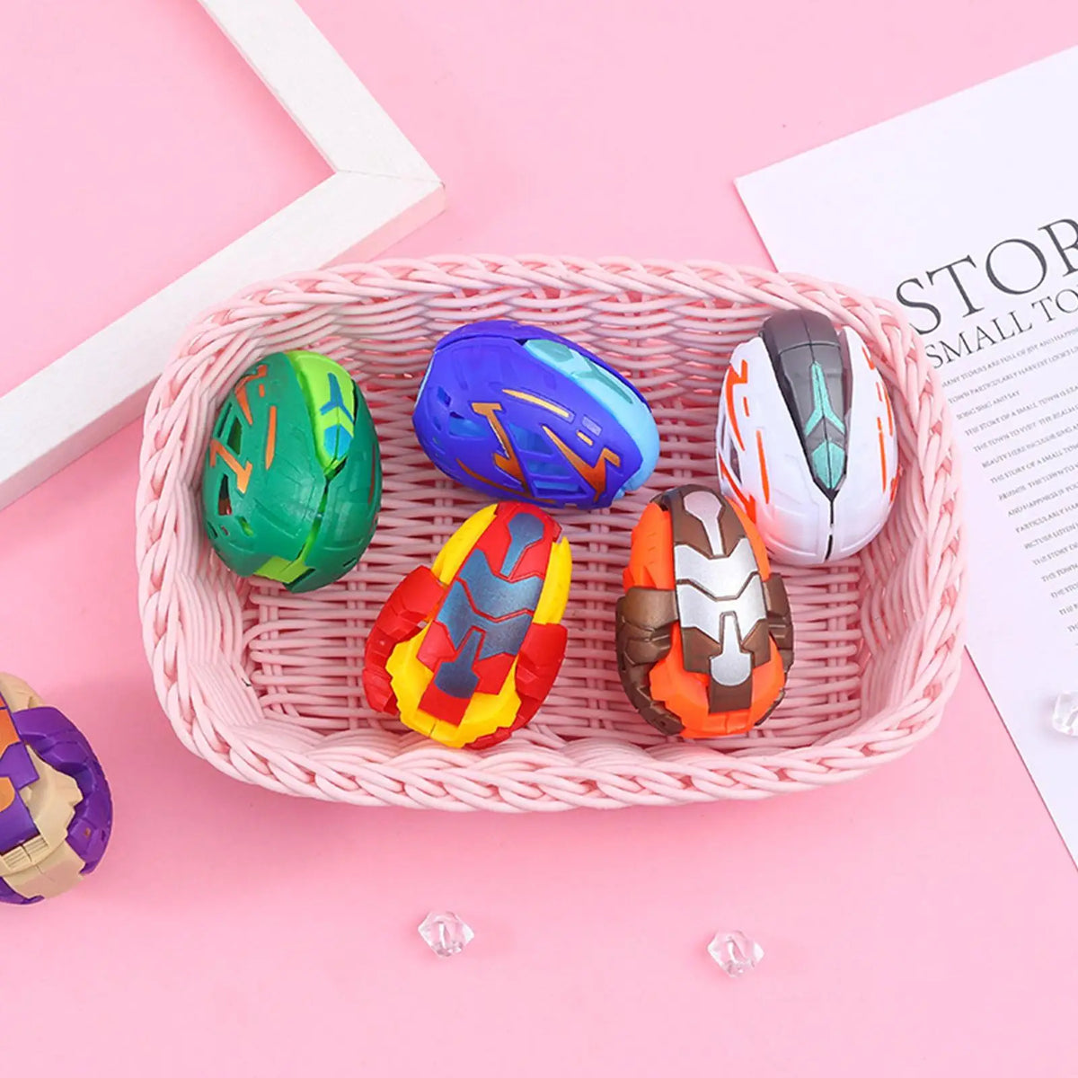 A pink woven basket holds several colorful dinosaur egg toys in various shades of green, blue, orange, and gray.