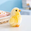 A fluffy yellow chick plush toy with orange beak sitting on a white surface.