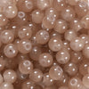 A close-up view of small, round, translucent pink glass beads for DIY jewelry making.