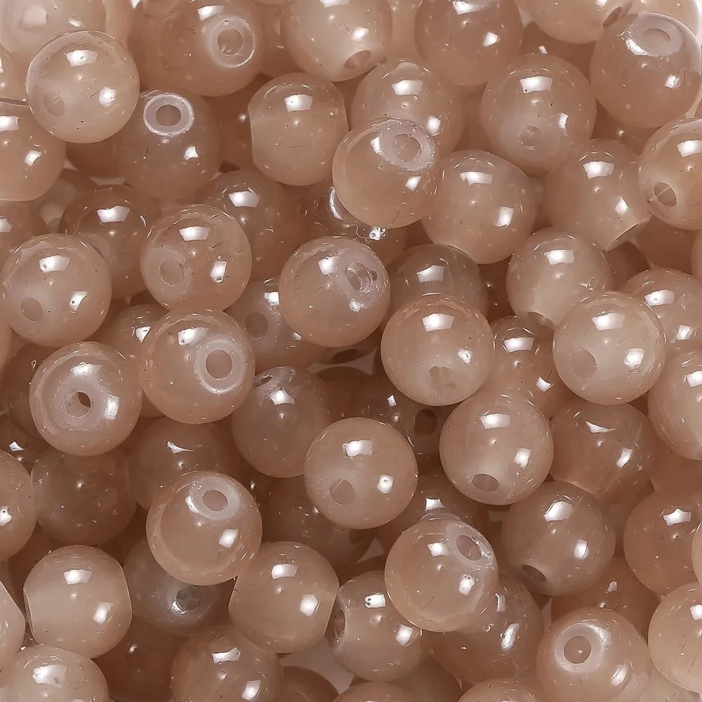A close-up view of small, round, translucent pink glass beads for DIY jewelry making.
