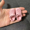 A pair of pink fashion slippers for 1/6 BJD dolls are held in a person's hand.