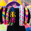 Assortment of colorful loom band bracelets and string crafts displayed on a black surface.