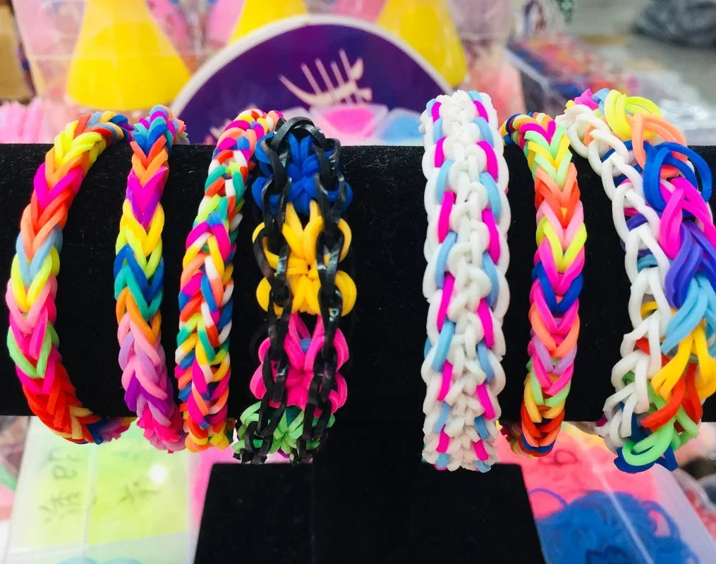 Assortment of colorful loom band bracelets and string crafts displayed on a black surface.