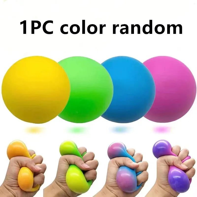 A hand holds a colorful slow rising squishy stress ball with various shades of yellow, green, blue, and purple.