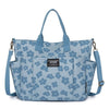 A light blue floral canvas tote bag with multiple exterior pockets.