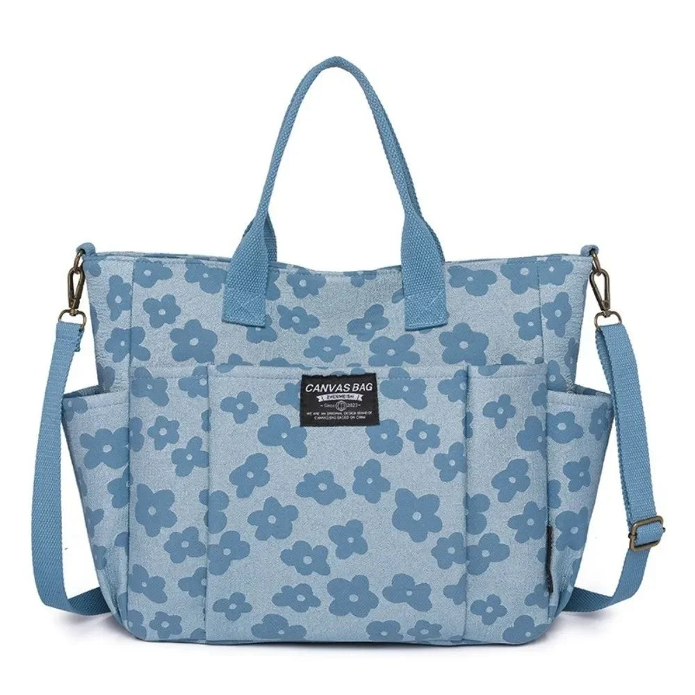 A light blue floral canvas tote bag with multiple exterior pockets.