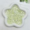 A white, five-pointed mold filled with clear, iridescent green acrylic ice strips for nail art and crafts.
