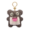 A gray and white plush monster with large eyes and a pink tongue attached to a gold-colored keychain.