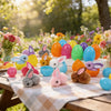 Assortiment coloré d'œufs de Pâques et de lapins en peluche sur une nappe à carreaux, en extérieur.