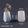 A white silicone mold shaped like a vase or planter, next to a dried floral sprig.