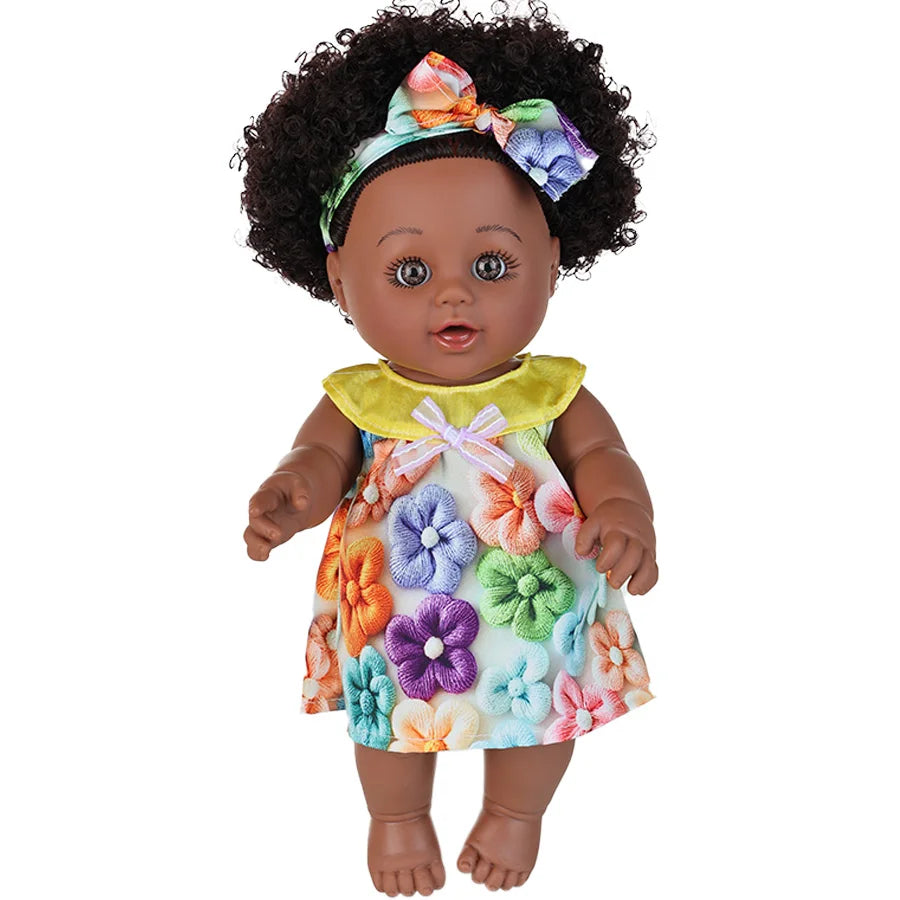 A 12-inch realistic African American baby doll with dark curly hair wearing a yellow top and a floral dress.