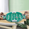 A portable tabletop foosball game with green and white components is set up on a wooden table.