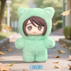 A plush toy resembling Gojo Satoru wearing a green hoodie is shown outdoors on a wooden path.