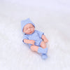 A realistic soft vinyl baby doll wearing a blue striped outfit and matching hat, lying on white fabric.