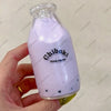 A hand holds a purple liquid in a glass bottle, which is identified as a Chiboki drink cup toy.