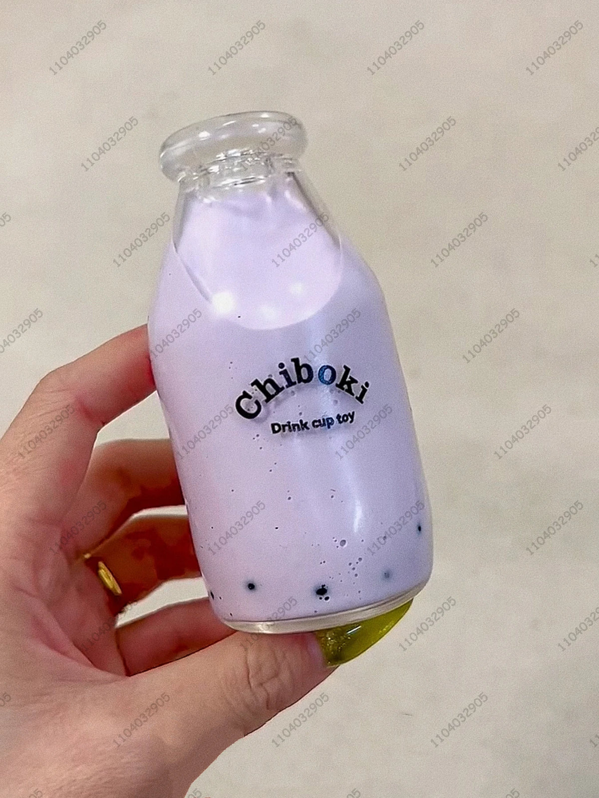 A hand holds a purple liquid in a glass bottle, which is identified as a Chiboki drink cup toy.