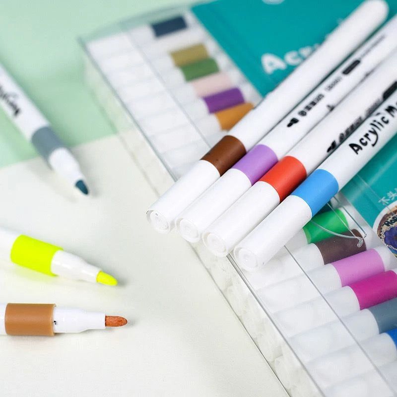 A collection of acrylic art markers in various colors is displayed in a plastic case.