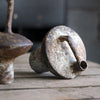 A vintage handcrafted ceramic vase with a mottled brown and beige finish sits on a wooden surface.