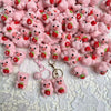 A pile of handmade crochet mini pig keychains in various shades of pink and red.