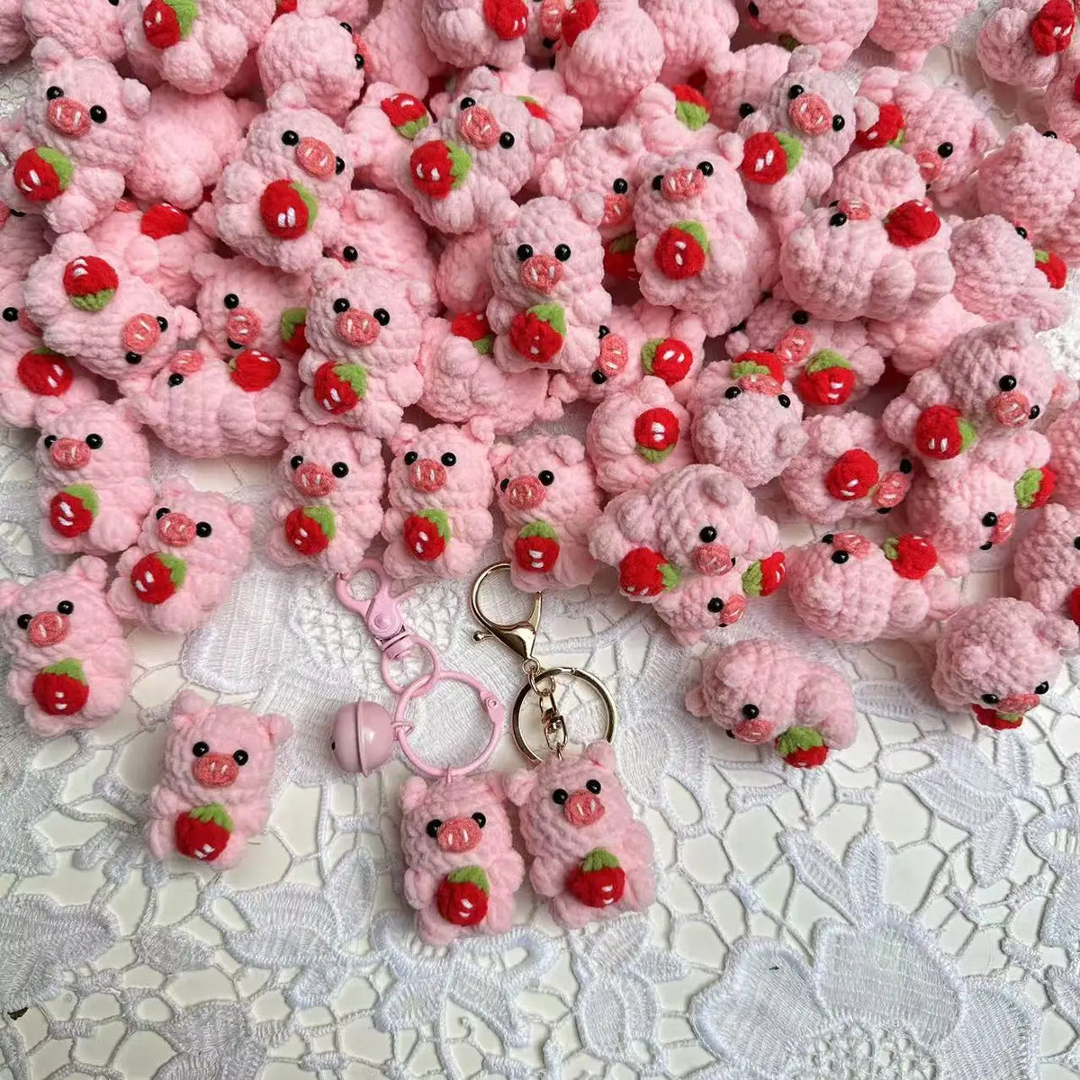 A pile of handmade crochet mini pig keychains in various shades of pink and red.