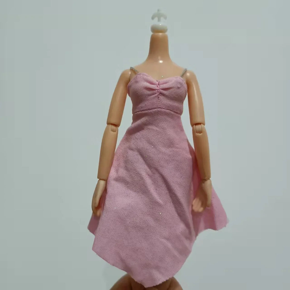 A pink dress and accessories for a 30cm doll fashion set displayed on a mannequin.