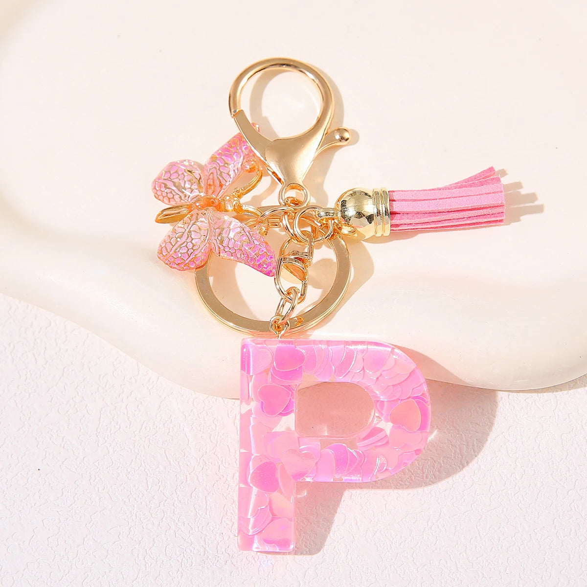 Gold initial heart keychain featuring a pink butterfly charm and pink tassel