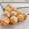 A collection of ten translucent amber acrylic D20 dice arranged on a wooden surface.