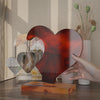 A heart-shaped silicone mold for resin casting, featuring a deep reddish-brown color, resting on a wooden surface.