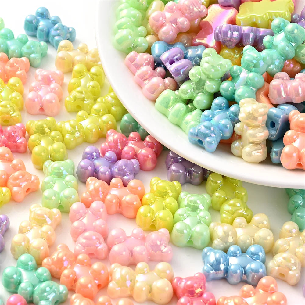 A close-up view of numerous pastel bear-shaped acrylic craft beads in various shades of pink, green, yellow, and blue.