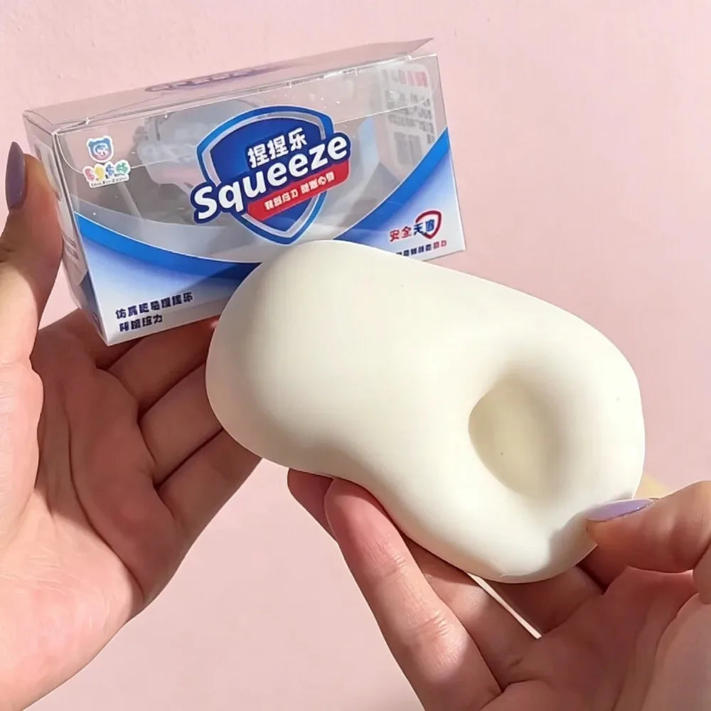 A hand holds a white squishy stress ball product packaged in clear plastic.