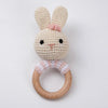 A handmade cream-colored rabbit rattle and teether ring made of wood.