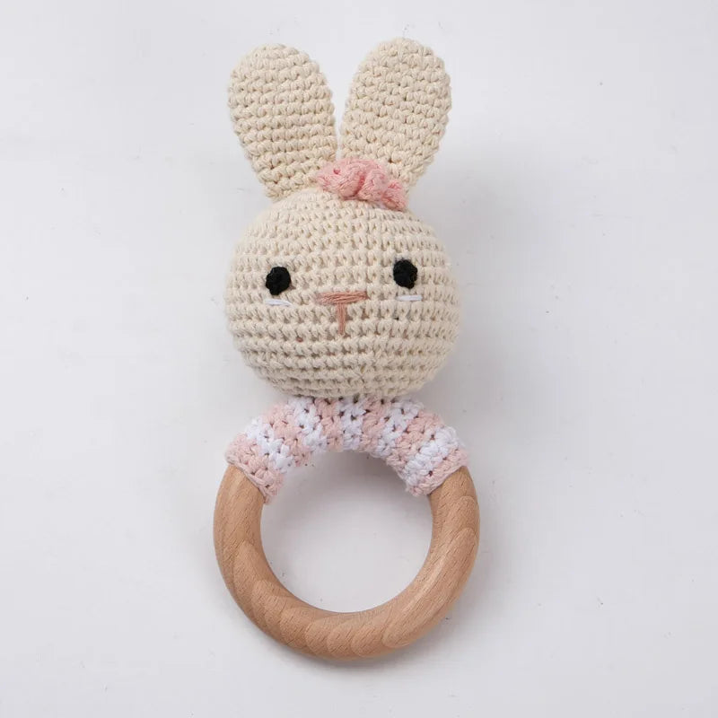 A handmade cream-colored rabbit rattle and teether ring made of wood.