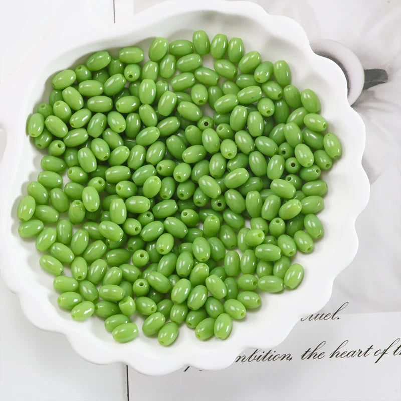 A pile of bright green oval glass rice grain beads for jewelry making displayed in a white dish.