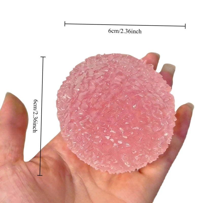 A pink squishy ice ball fidget toy is held in a hand, showing its texture and size.