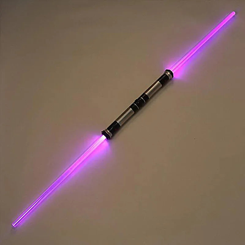 A glowing purple lightsaber toy with a metallic hilt and blade, lying diagonally on a light surface.
